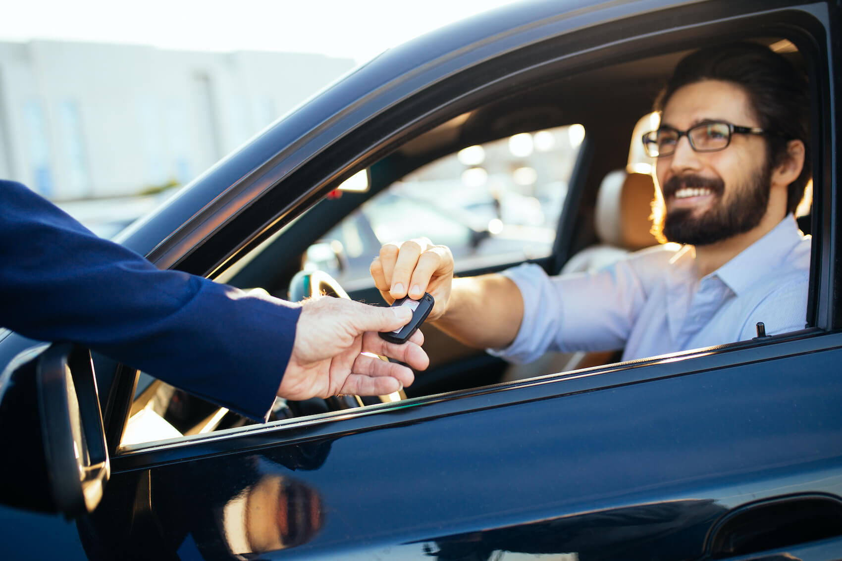 Man smiling while receiving keys to a pre-owned vehicle