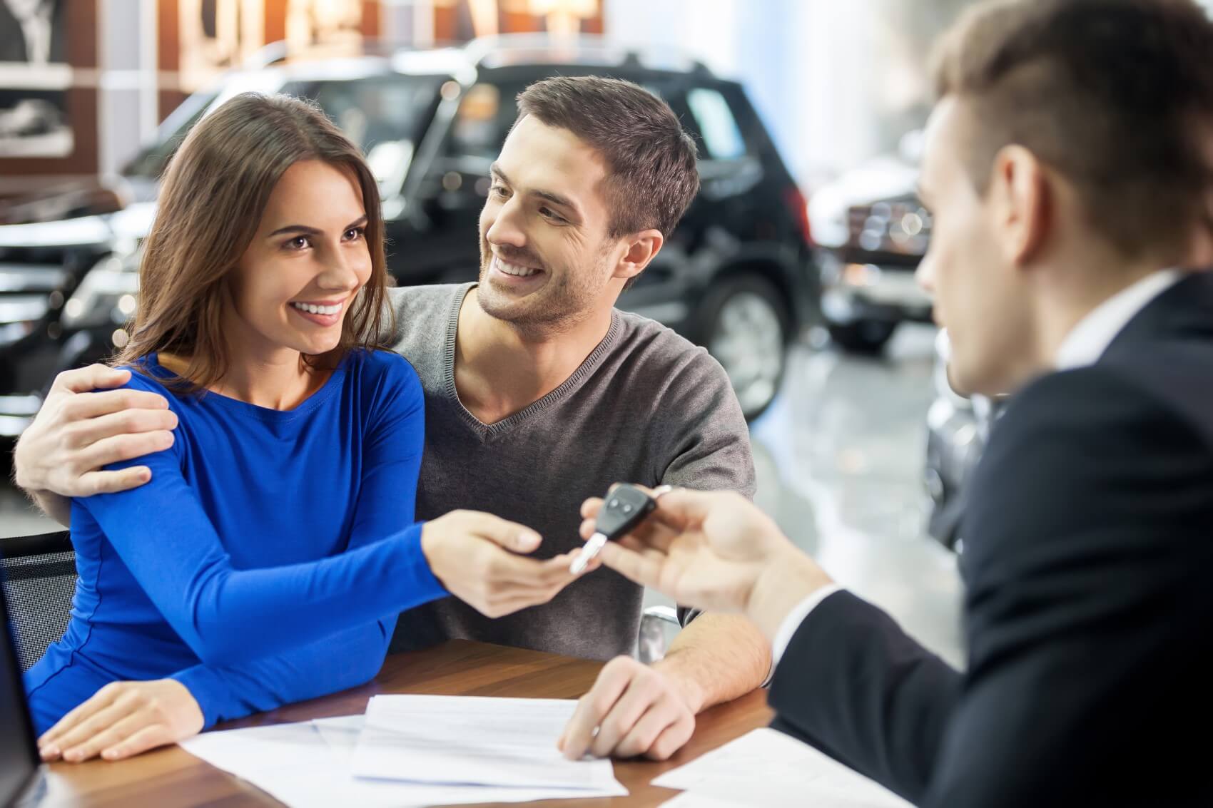 Couple receiving keys to their pre-owned car from a dealership representative
