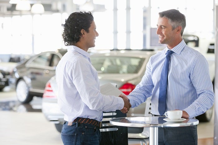 shaking hands in car showroom